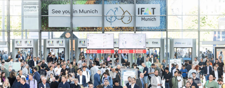 Besuchermenge im Eingang West der IFAT Munich Messe mit Ankündigung für 2026 auf großen digitalen Werbeflächen.