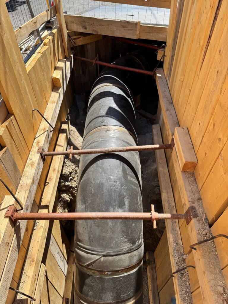 Wien stärkt das Rückgrat seiner Wasserversorgung 1 Schwarzes Rohr in einem mit Holzbohlen und Metallstreben gesicherten Rohrgraben auf einer Baustelle.