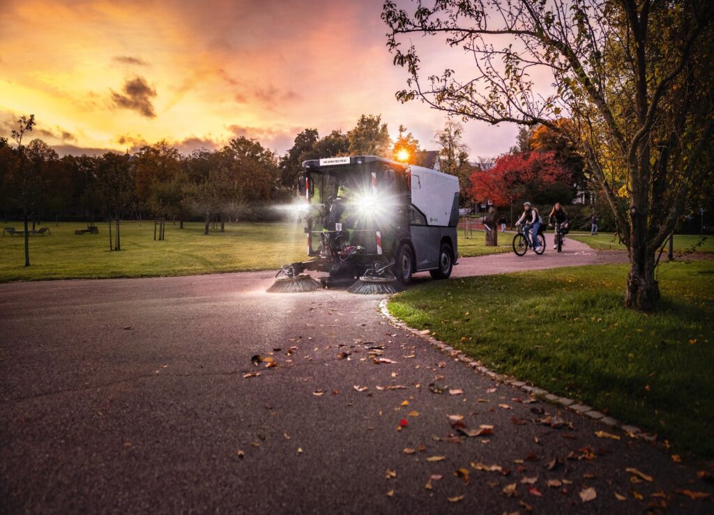 Kärcher präsentiert emissionsfreie Kommunaltechnik auf der Suisse Public 2026 4 Elektrische Kehrmaschine MC 250 mit 2-Besen-System bei der Stadtreinigung im Park während der Morgendämmerung.