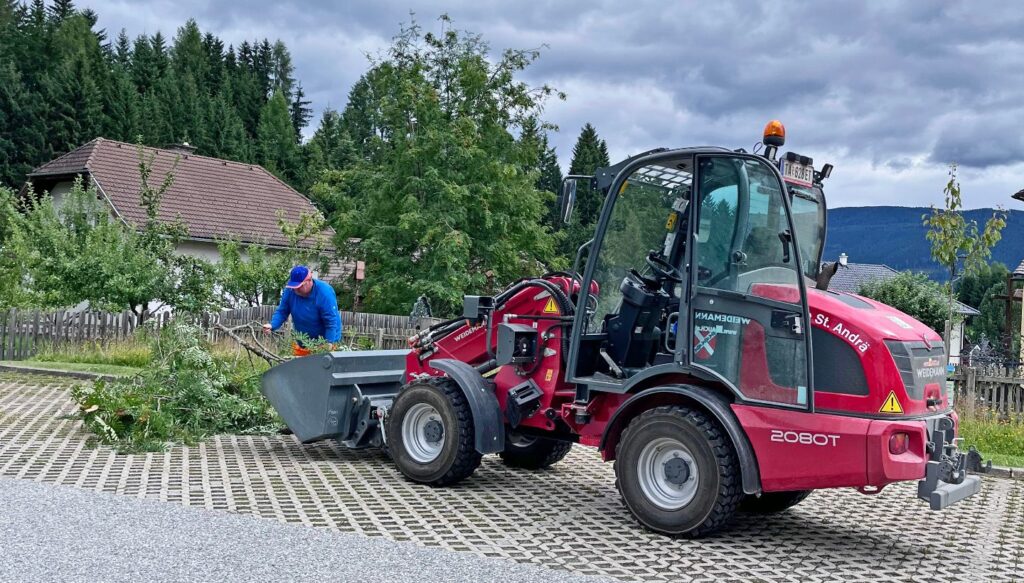 Mauch punktet mit Kompetenz und Verlässlichkeit im Kommunalbereich 5 Weidemann Teleskopradlader bei Gartenarbeiten in St. Andrä im Lungau belädt Schaufel mit Grünschnitt vor Wohnhäusern.