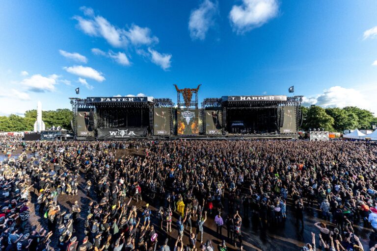 Dirkschneider-Konzert auf dem Wacken Open Air: Große Menschenmenge vor den Faster & Harder Stages unter blauem Himmel.