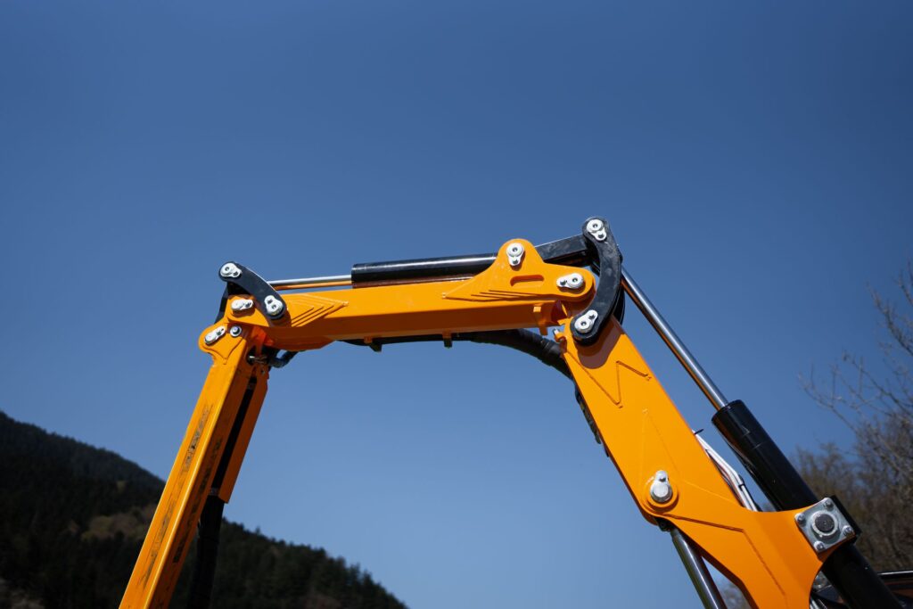 Detailansicht der Gelenke und Hydraulikzylinder eines gelben MULAG FBX Prototyp Auslegers vor blauem Himmel.