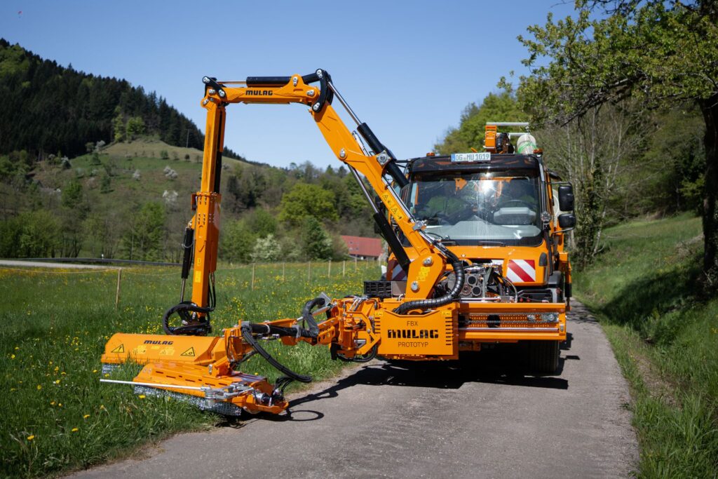 Mulag FBX Prototyp und MHU 900 Mähgerät in Frontansicht an einem Unimog auf einem Feldweg im Einsatz.