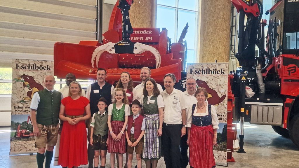 Familie und Ehrengäste in Tracht vor einer Eschlböck Biber Holzhackmaschine in einer Industriehalle.